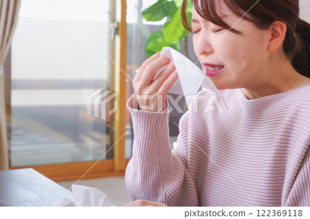 Young Asian woman painfully blowing her runny nose Young Asian woman painfully blowing her runny nose 122369118