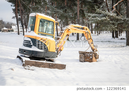 Abandoned excavator in the snow on a winter day due to unsuitable season for construction works Abandoned excavator in the snow on a winter day due to unsuitable season for construction works 122369141