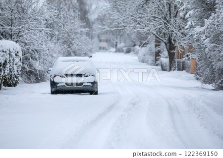 Snow-covered road and car covered in snow, road conditions in winter before road clearing 122369150