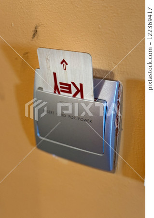 The key card is inserted into a switch in a modern hotel room to turn on the power of the guest's electrical presence system. Close-up 122369417