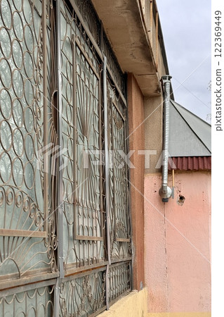A metal pipe is attached to the wall of a brick building, which removes smoke from the room. This is a device for air circulation 122369449