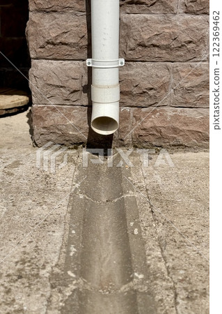 Detailed closeup view of a PVC downspout connected to a weathered brick wall in rustic outdoor setting Detailed closeup view of a PVC downspout connected to a weathered brick wall in rustic outdoor setting 122369462