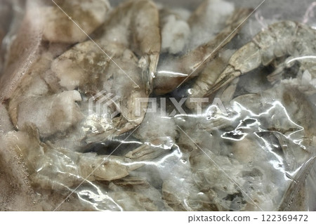 Frozen white shrimps in a transparent bag in the refrigerator at the supermarket. Close-up Frozen white shrimps in a transparent bag in the refrigerator at the supermarket. Close-up 122369472