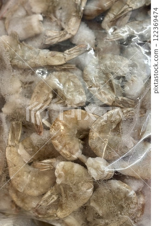 Frozen white shrimps in a transparent bag in the refrigerator at the supermarket. Close-up Frozen white shrimps in a transparent bag in the refrigerator at the supermarket. Close-up 122369474