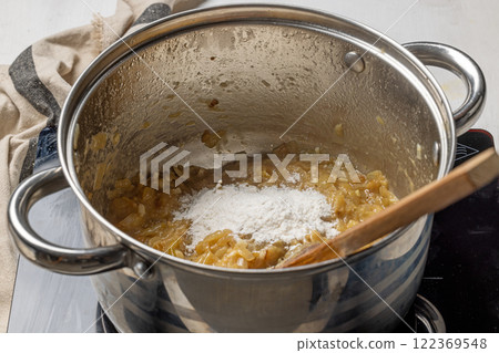 Adding flour to caramelized onions Adding flour to caramelized onions 122369548