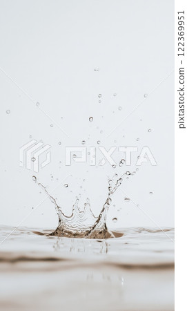 Crown shaped water splash rising from a calm water surface, creating ripples, droplets, and a sense of tranquility against a clean background 122369951