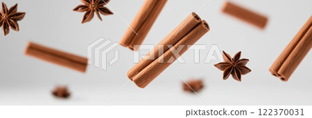 Cinnamon sticks and star anise are floating on a minimalist white background, creating a visually appealing arrangement that suggests warmth, spice, and aromatic flavors 122370031