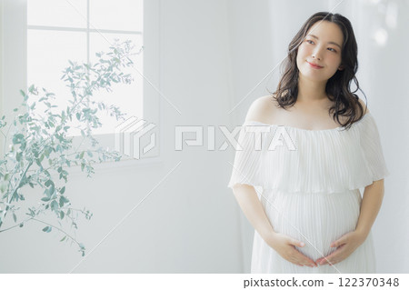 Pregnant woman standing by the window Pregnant woman standing by the window 122370348