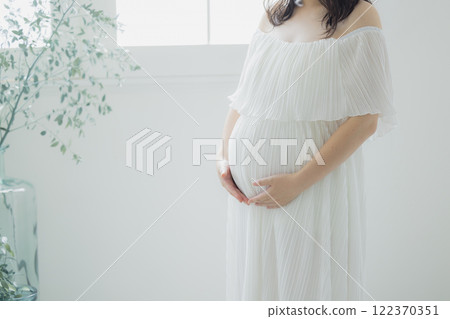 Pregnant woman standing by the window Pregnant woman standing by the window 122370351