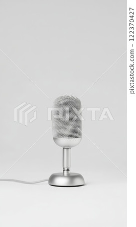 Silver microphone standing on a white background, ready for a singer to start singing or a comedian to begin their stand up comedy routine, capturing sound for music or voice recording 122370427