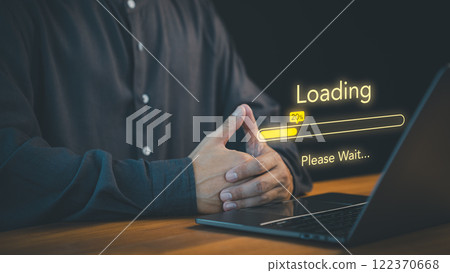 Person waits with a laptop screen displaying a "Loading" bar at 20%, accompanied by the text "Please Wait." Concept of digital processes, patience, and the anticipation of technology responding. Person waits with a laptop screen displaying a "Loading" bar at 20%, accompanied by the text "Please Wait." Concept of digital processes, patience, and the anticipation of technology responding. 122370668