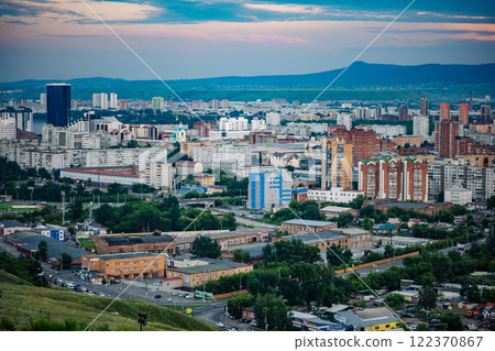 Krasnoyarsk, russia, city skyline featuring residential and industrial buildings at sunset with a mountain in the background 122370867