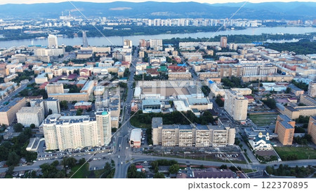 Aerial view of krasnoyarsk city center showcasing the yenisei river, central stadium, residential buildings, and urban infrastructure during the evening 122370895