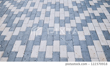 Geometric urban pavement with interlocking gray and white stones creating textured walkway surface pattern Geometric urban pavement with interlocking gray and white stones creating textured walkway surface pattern 122370918