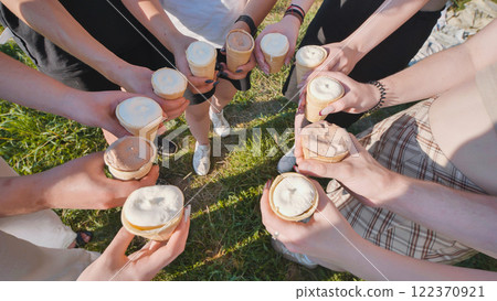 High school students are holding ice cream cones forming a circle on grass during a summer day 122370921
