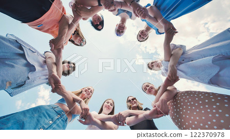 School friends holding hands in a circle, smiling and enjoying their time together outdoors 122370978