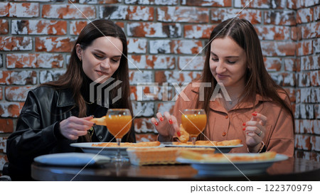 Two cheerful girls in a cafe having dinner. 122370979