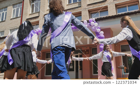 High school graduates in purple sashes celebrate their last day with a round dance in front of their school High school graduates in purple sashes celebrate their last day with a round dance in front of their school 122371034