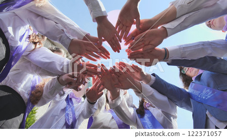 Cheerful students join hands in a circle, celebrating graduation and unity. The image captures joy, achievement, and hope for the future Cheerful students join hands in a circle, celebrating graduation and unity. The image captures joy, achievement, and hope for the future 122371057