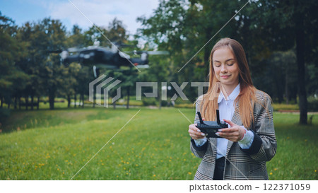 Businesswoman navigating an unmanned aerial vehicle in a park, showcasing innovation and technology in a natural setting Businesswoman navigating an unmanned aerial vehicle in a park, showcasing innovation and technology in a natural setting 122371059