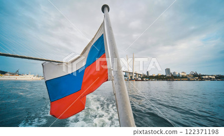 Russian flag waving from boat sailing in the eastern golden horn bay, near the zolotoy rog bridge in vladivostok, russia 122371198