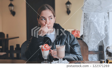 Customer enjoying sweet pastry and steaming coffee, sitting comfortably in warm cafe, surrounded by soft lighting and inviting ambiance 122371269