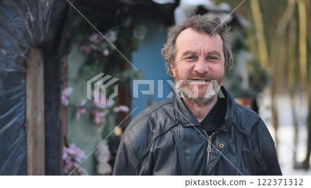 Homeless man smiling beside makeshift shelter, constructed from plastic sheets, adorned with artificial floral decorations Homeless man smiling beside makeshift shelter, constructed from plastic sheets, adorned with artificial floral decorations 122371312