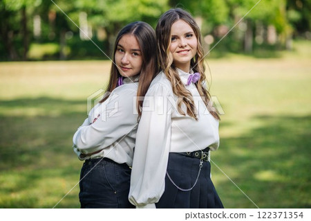 Two confident students stand back to back, ready for their first day of school, embracing the new academic year with optimism and excitement 122371354