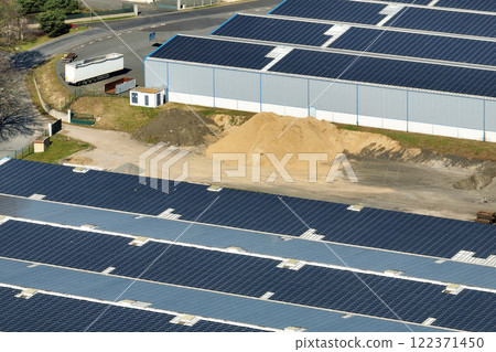 Aerial view of blue photovoltaic solar panels mounted on industrial building roof for producing green ecological electricity. Production of sustainable energy concept Aerial view of blue photovoltaic solar panels mounted on industrial building roof for producing green ecological electricity. Production of sustainable energy concept 122371450