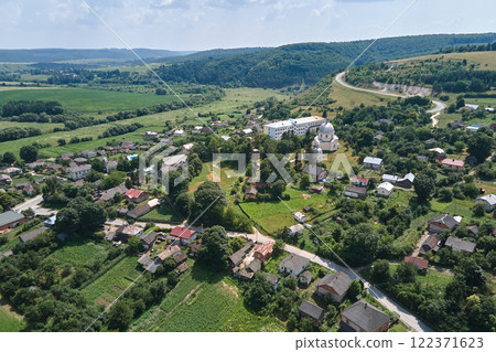 Aerial landscape view of village houses and distant green cultivated agricultural fields with growing crops on bright summer day 122371623