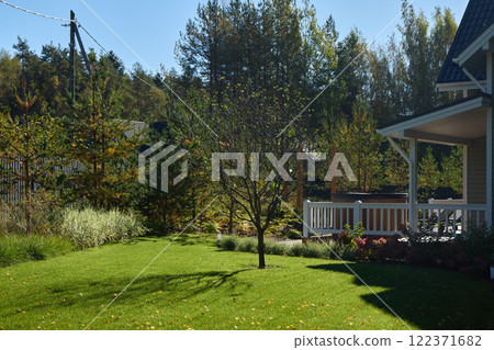 A Serene and Picturesque Backyard Featuring Lush Green Grass, Vibrant Trees, and Natures Beauty 122371682