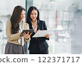Two colleagues engaged in business analytics, using digital tablets over financial charts. Colleagues Collaborating with Tablets on Business Analytics. 122371717