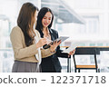 Two colleagues engaged in business analytics, using digital tablets over financial charts. Colleagues Collaborating with Tablets on Business Analytics. 122371718
