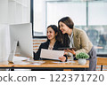 Two colleagues engaged in business analytics, using digital tablets over financial charts. Colleagues Collaborating with Tablets on Business Analytics. 122371720
