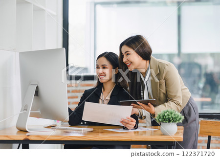 Two colleagues engaged in business analytics, using digital tablets over financial charts. Colleagues Collaborating with Tablets on Business Analytics. 122371720