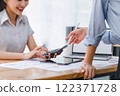 Two colleagues engaged in business analytics, using digital tablets over financial charts. Colleagues Collaborating with Tablets on Business Analytics. 122371728