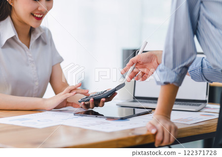 Two colleagues engaged in business analytics, using digital tablets over financial charts. Colleagues Collaborating with Tablets on Business Analytics. 122371728