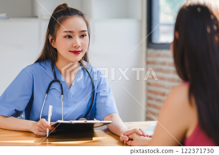 Female nurse jotting down health information during a consultation with a patient, dedicated medical care. 122371730