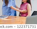 A nurse offers reassuring care by holding a patient's hand during a medical consultation, creating a supportive and empathetic atmosphere. 122371731