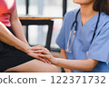 A nurse offers reassuring care by holding a patient's hand during a medical consultation, creating a supportive and empathetic atmosphere. 122371732