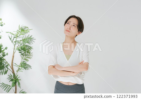 A woman in her 30s wearing yoga wear and crossing her arms 122371993