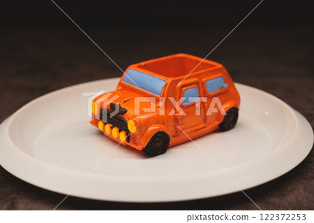 A brilliantly crafted and creative dessert shaped like an orange car displayed artfully on a plate A brilliantly crafted and creative dessert shaped like an orange car displayed artfully on a plate 122372253
