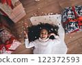 Excited black little girl lying on floor with gift boxes and colorful confetti 122372593