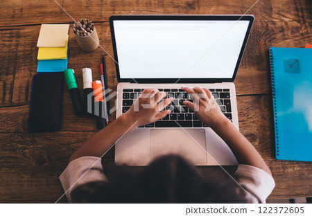 Crop unrecognizable kid working on laptop over wooden table 122372605