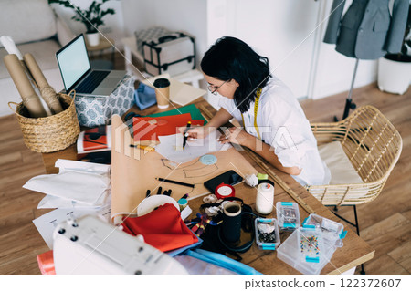 Focused female designer drawing on paper in workshop 122372607