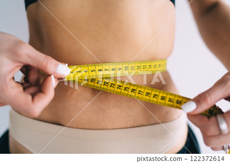 Slim woman measuring waist with tape Slim woman measuring waist with tape 122372614