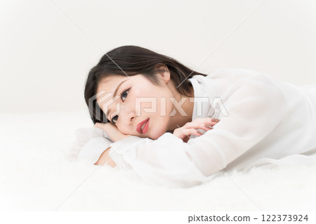 Beauty image: A young woman lying down in a white shirt, ennui Beauty image: A young woman lying down in a white shirt, ennui 122373924