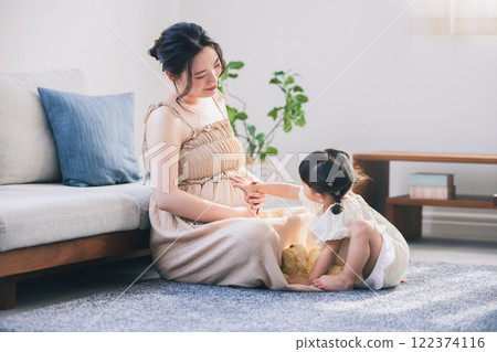 Daughter touching mother's belly Daughter touching mother's belly 122374116