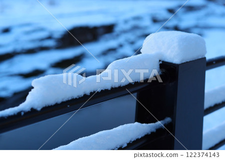 A Beautiful SnowCovered Railing Surrounded by a Picturesque Winter Landscape Scene 122374143