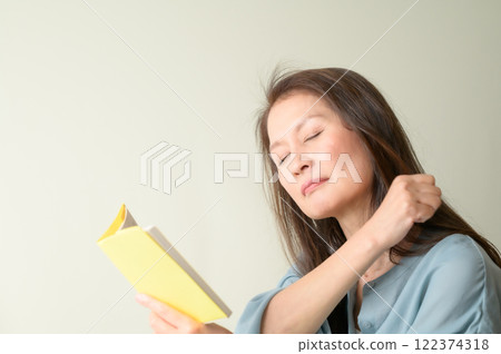 Senior woman massaging her shoulders while reading Senior woman massaging her shoulders while reading 122374318